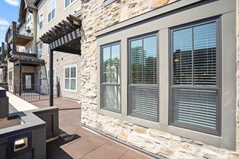 A stone building with a balcony and a window with blinds at Mirabelle Luxury Apartments, Missouri